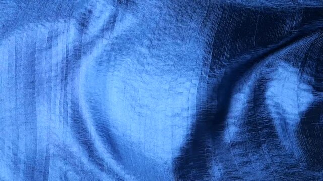 Blue natural silk fabric waving in the wind. Abstract waves and ripples on smooth textile background. Elegant texture of shiny material with linear pattern. Soft motion of luxury fabric.