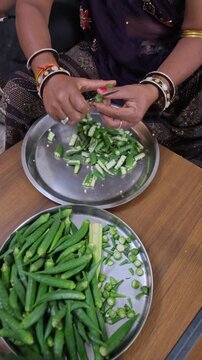 Close up of an Indian woman hands cutting fresh okra or bhindi