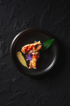 Gourmet Crab Plated With Sauce And Edible Flowers On Black Plate For Fine Dining Presentation