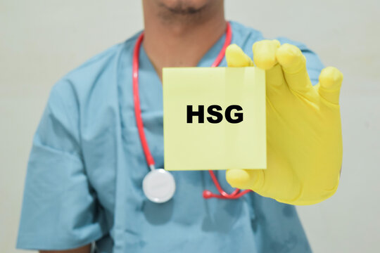 Doctor holds in hands a card with the name of the HSG - Hysterosalpingography. Medical concept