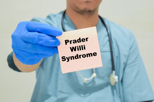 Doctor holds in hands a card with the name of the Prader Willi syndrome. Medical concept