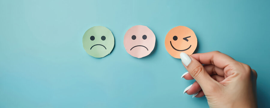 Woman hand chooses happy face icon over sad ones. Concept for customer satisfaction positive feedback and excellent service review. Opinion matters.