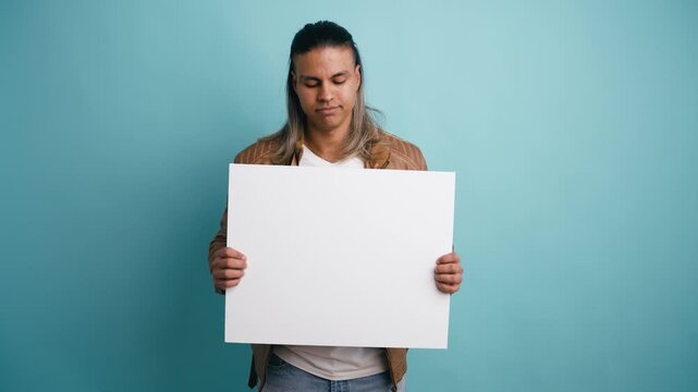 Young hispanic man with long hair standing against a blue background, holding a blank white sign. He shows various expressions, smiling
