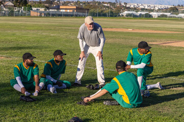 Fototapeta premium Vertical video: Calling coach coaching players on turf by mound for drill, green jerseys, gloves