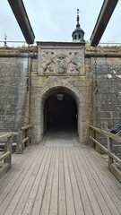 Historic stone gateway at Kalmar Castle with carved coat of arms, wooden drawbridge chains and medieval architecture under an overcast sky. © Pim