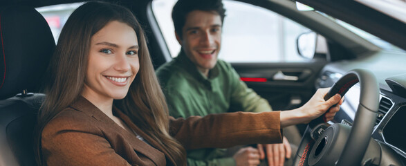 Obraz premium Two friends sit inside a car, smiling and sharing a moment together. The environment has a modern feel, with bright lights and a lively city backdrop suggesting a casual outing.