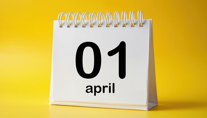 Fototapeta premium Desk calendar shows 01 April date. Reminder for Fools Day celebration. Empty space for custom text or pranks. Yellow background. Holiday event planning.