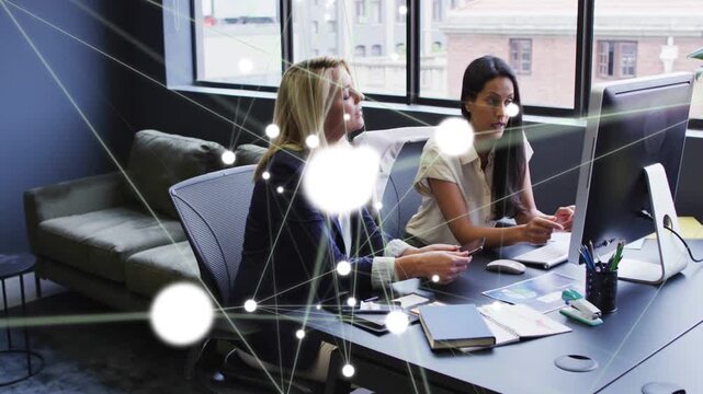 Vertical video: Two businesswomen clicking mouse causing nodes and flares obscure then show data