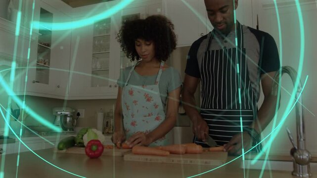 Couple starting cooking at island chopping carrots on boards while teal overlay sweeping over hands