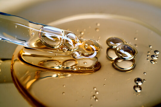 Pipette drawing golden liquid serum with bubbles