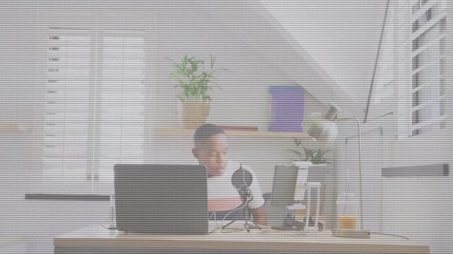 Male student rising from chair, pulling chair in and adjusting laptop and mic for recording