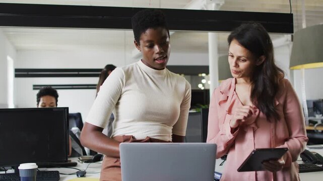Two colleagues sharing laptop after quick glance, left typing, right pointing, finalizing review