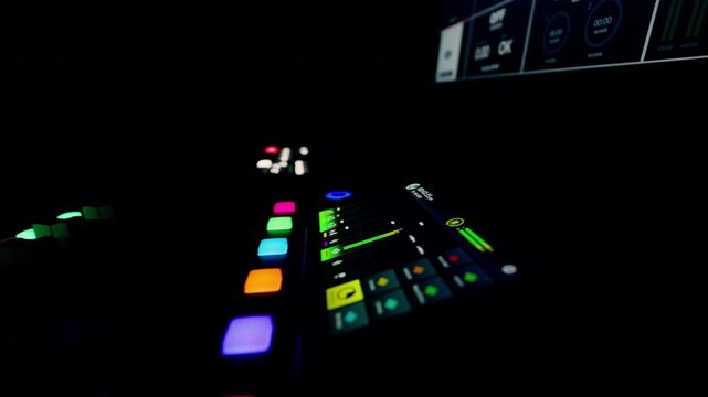 Audio mixer controls glowing buttons dark studio. Digital sound console interface display monitoring levels. Podcasting broadcasting equipment music production technology. Colorful LED lights electron