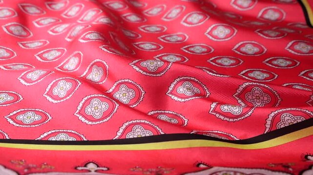 Natural silk fabric with oriental pattern fluttering in the wind. Red textile creates abstract waves and smooth motion background. Detailed view of traditional ornament on flowing material.