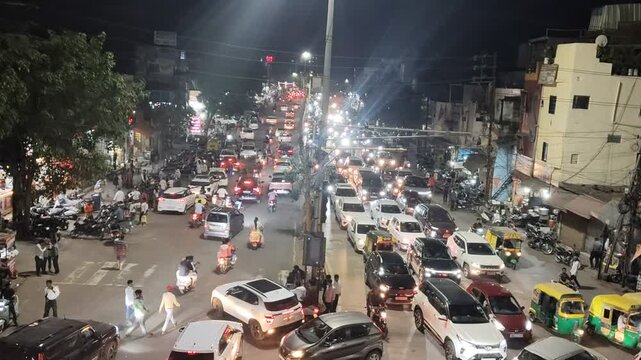 Busy night traffic on a crowded urban street in India with cars, bikes, auto rickshaws and pedestrians. City life and congestion captured with bright lights and active marketplace atmosphere. India, 