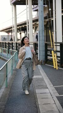 Elegant Japanese woman commuting to work in the morning, walking next to a railway station