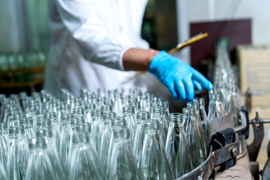 Close up hands of factory worker check the quality of the bottle before use for contain the drinking liquid in drinking factory workplace.
