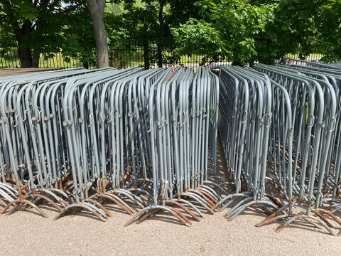 Control barriers, side view, Row of metal crowd control barriers stacked in outdoor storage area.