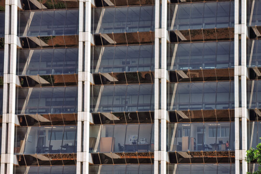 Modern Glass Facade of Office Building with Interior View  office interiors with desks and equipment