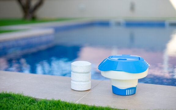 Plastic chlorine floater and stacked tablets on the edge of a swimming pool - pool maintenance concept
