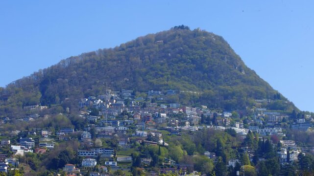 Monte Bre with residential houses on the hillside and blue sky, Lugano, Switzerland