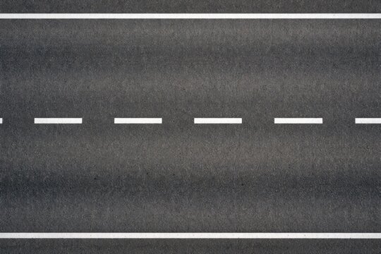 Birds eye photo of a level tar road showcasing detailed white dividing stripes