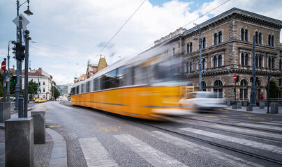 Fototapeta premium Yellow City Tram Rushes Blurred In Motion On A Central Street In Budapest