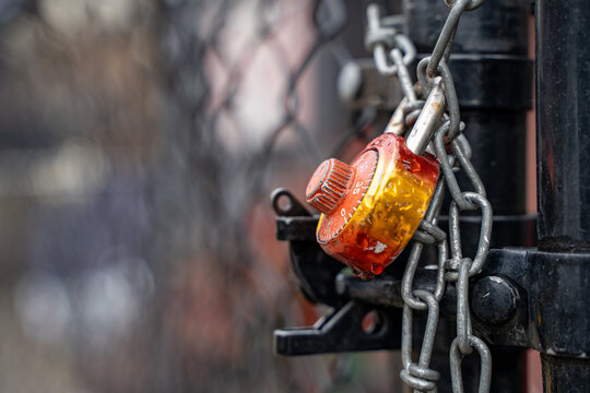 Close up of combination padlock and chain on metal gate in rain.