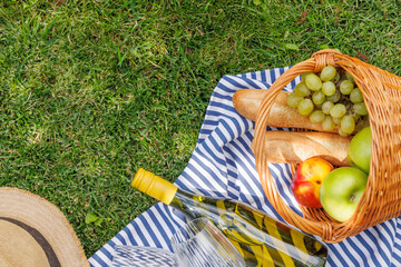 Fototapeta premium Picnic with wine, fruits, and baguette on a green meadow