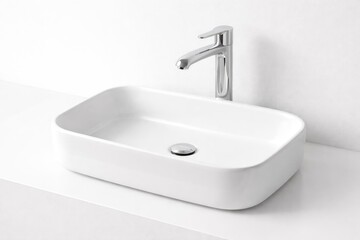 Fototapeta premium minimalist white ceramic sink paired with a polished faucet over a white backdrop