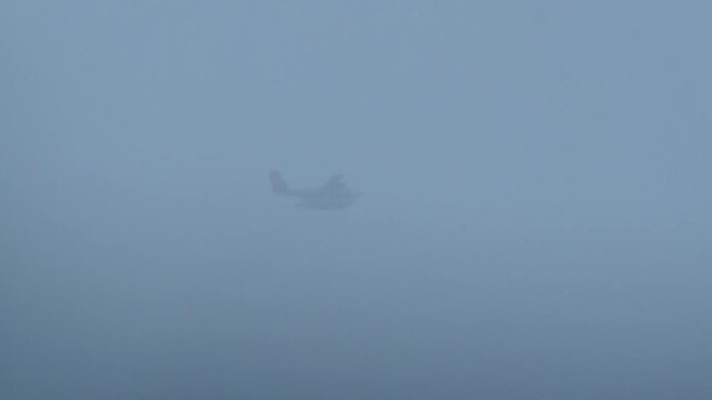 Foggy Seaplane Silhouette Over Water Coastal Floatplane Flying Through Heavy Drizzle And Low Visibility During Stormy Overcast Morning, Distant Redtailed Aircraft Blurred Above Calm Waves, Moody