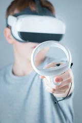 A gamer wearing virtual reality glasses with controllers and a headset © Alexander