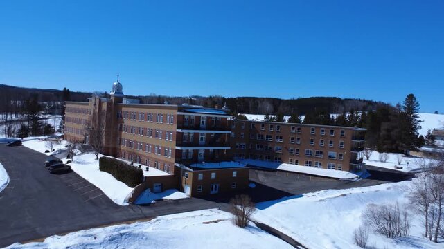 Cinematic drone view of the ornate bell tower at the Servants of Our Lady Queen of the Clergy convent. Capturing architectural heritage in Lac-au-Saumon, Quebec.