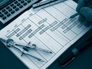 Hand drawing a project schedule chart in a notebook with technical drafting tools © FERNANDO