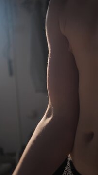 Vertical video teenage boy uses adjustable 5 kg dumbbell to perform biceps curl. Young man trains muscles in morning at sunrise or sunset. Teen wants to be strong and healthy.