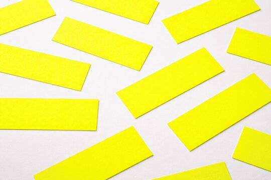 Bright fluorescent yellow rectangular labels arranged on a smooth white background