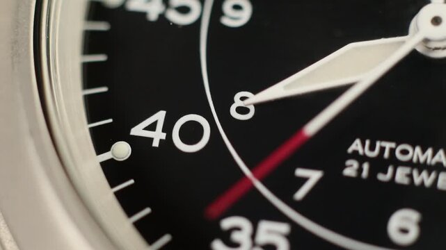 Macro close up of an automatic mechanical field watch with moving arms
