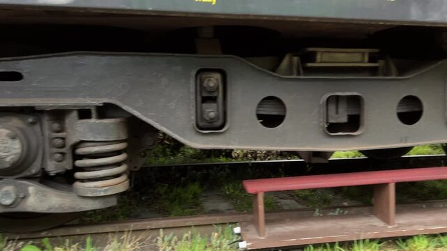 Cinematic slide shot from left to right of a vintage train carriage bogie and suspension system, industrial railway transport detail