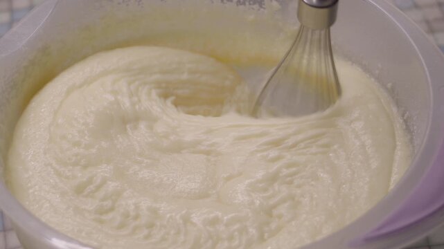 Close-up of kitchen mixer whipping buttercream in plastic bowl