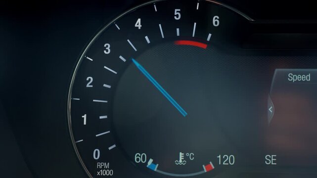 Close up of illuminated car tachometer on dashboard with blue needle showing engine RPM. Concept of driving, vehicle control, speed and automotive technology