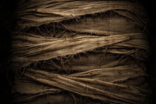 Dark background showing distressed worn mummy bandage texture with natural frayed horizontal layering