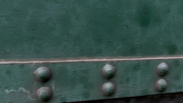 Close-up slide shot moving right to left over vintage train carriage metal riveting, industrial texture detail