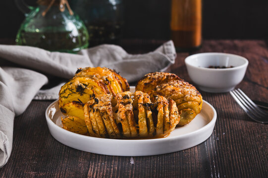 Baked Hasselback potatoes with cheese, garlic and herbs on a plate on the table