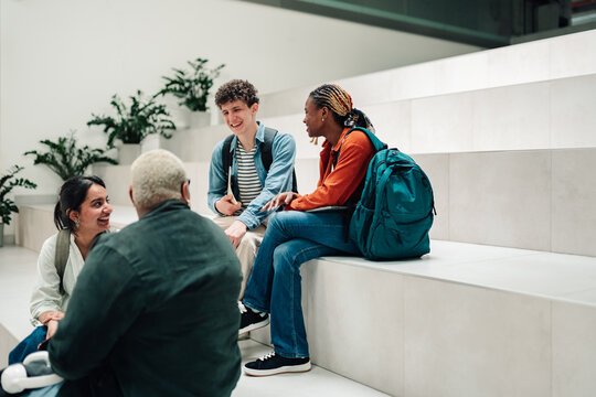 Diverse students conversing and learning together on campus steps, sharing ideas and building friendships