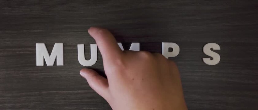 the word mumps written on a dark background with white block letters or capital letters (fast version)