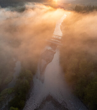Aerial view of the Foothills Trail bridge and river shrouded in a golden mist, kissed by the rising sun, Orting, Washington, United States.