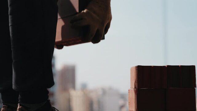 Worker moving bricks from stack at construction site