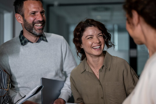 Coworkers laughing cheerfully while discussing business in office