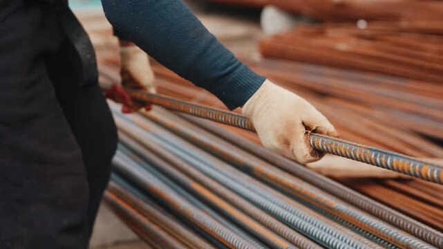Worker rearranging steel rebar rods on construction site