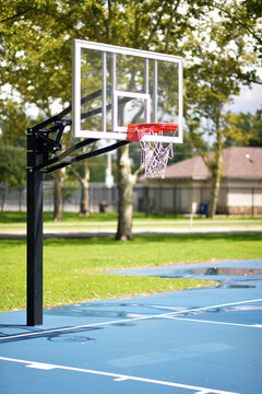 Calm Neighborhood Park Illuminated By Sunlight Showcasing Basketball Net And Rowhouses. New York